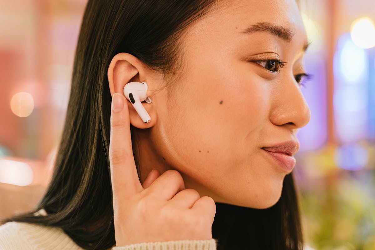 Woman inserting wireless earbud to talk to AI
